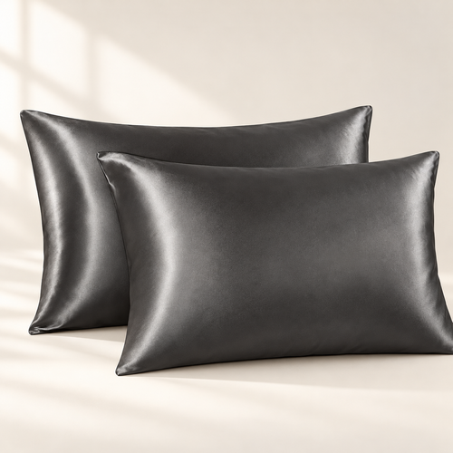 Two dark grey satin pillowcases on a warm ivory background